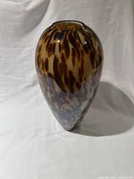 Tall heavy glass vase with brown and amber mottled pattern shown from front angle