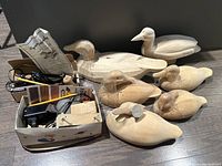 Overview of six hand-carved wood duck decoys and assorted carving tools and accessories in cardboard boxes.