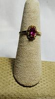 Front view showing ring mounted on display finger, highlighting the marquise-shaped pink stone and gold band.