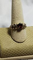 Front view of the 14K gold ring showing the oval red garnet stone centered on the decorative crisscross band.