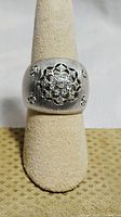 Front view of sterling silver ring with floral white sapphire design on beige stand