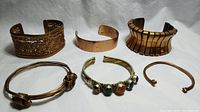 All six handmade copper and mixed metal bracelets displayed together on a white background.