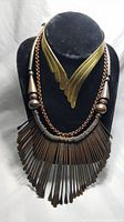 Full view of three necklaces displayed on a black velvet bust showing copper chain, bronze spikes, and brass collar necklace.