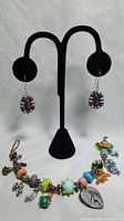 Full view of the Navajo-style colorful semi-precious stone earrings on a display stand with the matching charm bracelet laid out below.