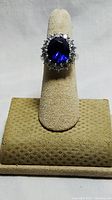 Front view of the ring showing the deep blue oval center stone with surrounding crystals and silver band.