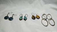 Four sets of sterling silver earrings with semi-precious stones displayed on a white background.