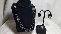 Full view of the Silpada sterling silver and wood necklace with large oval links and rectangular wood beads displayed on a black bust, with matching black onyx wire mesh pendant and earrings on black display stands.