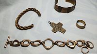 Overview of copper jewelry lot showing twisted wire bracelet, solid copper cuff, chain link bracelet, cross pendant, and ring.
