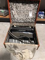 Accordion in open case showing the instrument, keys, and interior lining.