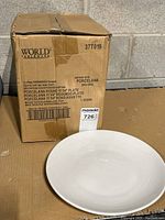 Box labeled World Tableware with 12 round plates inside. Box shows product details specifying 11 1/4 inch porcelain plates.
