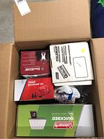 Photo of box interior showing boxed Coleman QuickPump 12V, GE SteelBEAM fluorescent lantern, and other packed items.