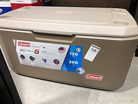 Closed view of the beige Coleman Xtreme 5 cooler with a white lid showing branding and capacity stickers.