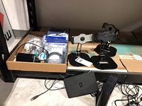 Overview of two external hard drives placed on table, three black iPad stands, and a box with assorted cables and connectors.