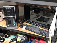 HP desktop tower and 22-inch HP monitor on shelf with wired keyboard and mouse in front.