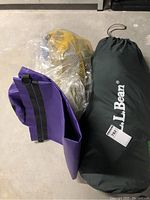 Photo showing L.L. Bean tent bag, purple ground mat, and sealed yellow and black mesh camping bag.