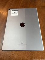 Rear view of the silver Apple iPad showing the Apple logo, maxsold sticker, and overall condition of the back casing.