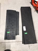 Two different types of rubber mats, one with a lip and checkered pattern, another with a diagonal line pattern on top side.