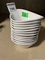 Stack of twelve white ceramic small bowls, showing the overall shape and size.