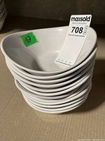 Stack of twelve small white triangular rounded bowls, showing front and top view, with slight dirt marks visible on bowl surfaces.