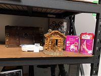 Shelf displays wooden chest, mattress encasement, birdhouse, manicure and pedicure kits and candle holders.