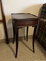 Full view of the solid wood end table showing its raised edges on top and the leg design with curved supports.
