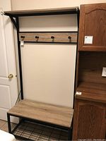 Full view of combined bench and coat rack showing top shelf, coat hooks, bench seat, and bottom storage