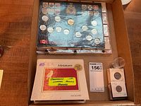 Top view showing cigar box lid with Canada 125 quarter set board, plastic coin tube and individual coin flips.