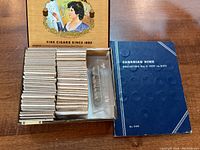 Open wooden cigar box showing stacks of cardboard coin holders and album beside it