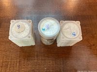 Three coin tubes top view showing white square and clear round tubes with hand-written markings