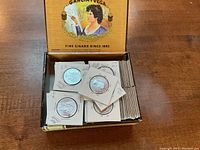 Open cigar box filled with Canada half dollars in individual cardboard holders