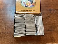 Wooden cigar box filled with stacked cardboard flips containing coins