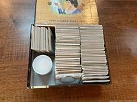 Open cigar box showing stacks of cardboard flips and plastic coin tube