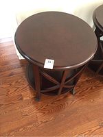 Front angle shot showing round table top, curved legs, crossbar support, and lower shelf.