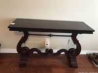 Front view of the Bombay Company hall table showing the rectangular wooden top and carved scroll legs with stretcher.