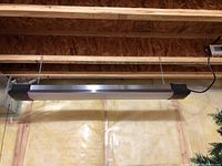 Full view of hanging bar lamp suspended from wooden beams by two chains, showing length and construction material.