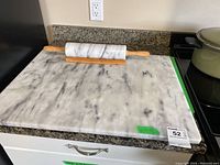 Marble slab and marble rolling pin on kitchen counter, showing overall shape, veining and usage marks