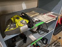 Ryobi orbital jigsaw placed on a shelf with instruction manual and some blades visible nearby