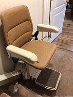 Chair mounted on lower end of rail showing upholstery, armrests, footrest