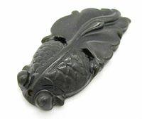 Close-up image showing detailed scales and fins carved into the black gemstone koi fish pendant from one side.