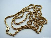Overall view of coiled gold rope twist chain necklace on white background