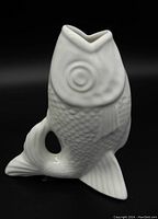 Front angle of white ceramic fish-shaped pitcher showing detailed scales and fish eye design