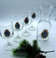 Full set including one carafe and four glasses with embossed branch crest and anniversary marking