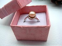 Ring displayed inside a pink textured gift box showing pearl and band design.