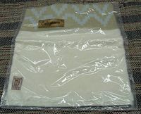 Photo showing folded Calamaco pampas alpaca pashmina shawl inside sealed plastic packaging, displaying part of the neutral color and tag.