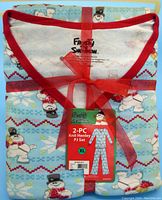 Folded pajama set tied with red ribbon showing part of pattern and tag