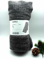 IKEA GURLI grey throw blanket rolled and wrapped in original packaging with label visible.