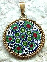 Front view of the round Murano glass pendant showing colorful millefiori floral pattern with red, green, white, and blue accents, set in twisted rope sterling silver frame.