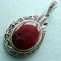 Close-up of the front view of the oval carnelian stone cabochon set in intricate sterling silver with marcasite stones surrounding it