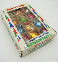 Box with twelve colorful vintage Santa Land Christmas ornaments in original packaging, showing product labeling and ornament compartments.