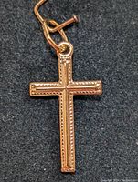 Front view of a 10K gold cross pendant showing detailed beaded edge design with loop for chain attachment against black background.